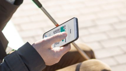 Close-up di una persona non vedente mentre utilizza uno smartphone.