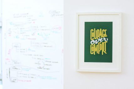 Foto di un quadro che recita " Courage over comfort"