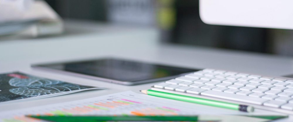 scrivania con matite, tastiera del computer e quaderni