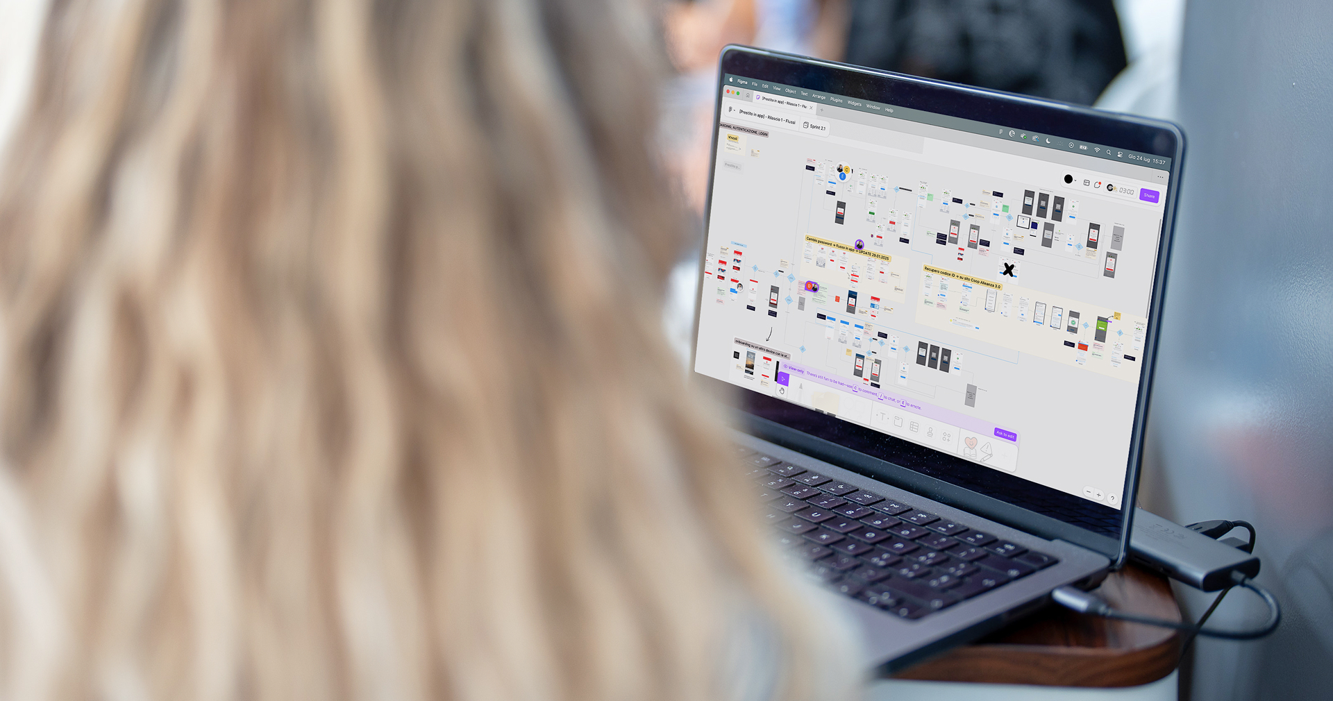 Persona al lavoro su una board digitale con i flussi e le schermate dell’app Coop.